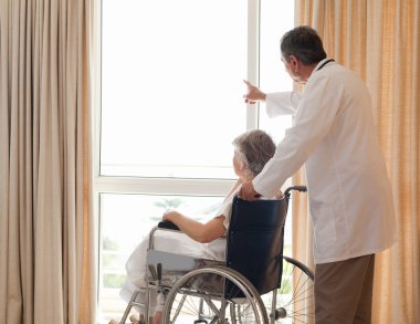 Doctor with his patient looking out the window clipart