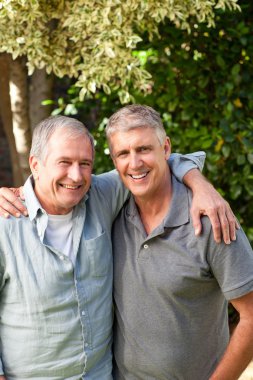 Father and his son looking at the camera in the garden clipart