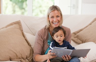 Mother looking at a book with her son clipart