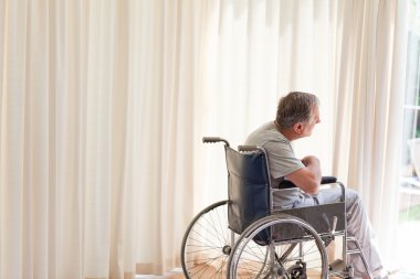 Man in his wheelchair looking out the window clipart