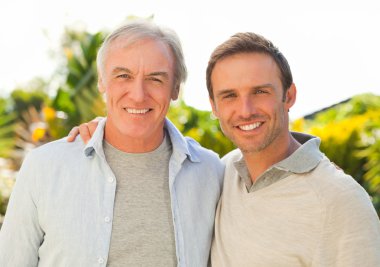 Father and his son looking at the camera in the garden clipart