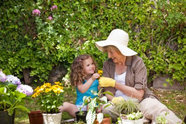 Happy Grandmother with her granddaughter working in the garden clipart