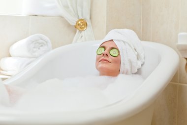 Relaxed woman taking a bath with a towel on her head clipart