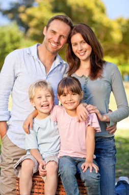 Smiling family picnicking in the park clipart