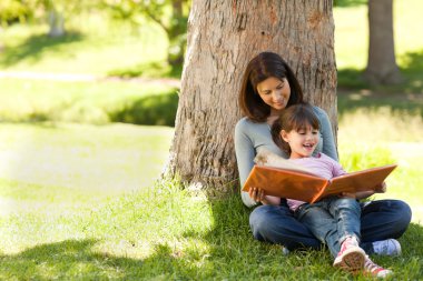 Radiant mother with her daughter looking at their album photo clipart