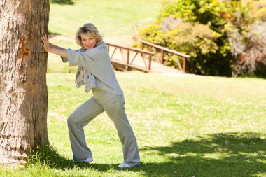 Mature woman doing her streches in the park clipart