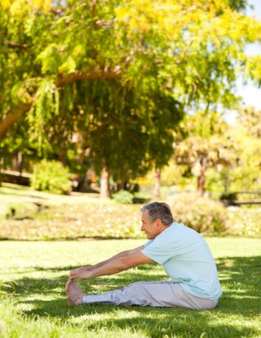 Mature man doing his streches in the park clipart