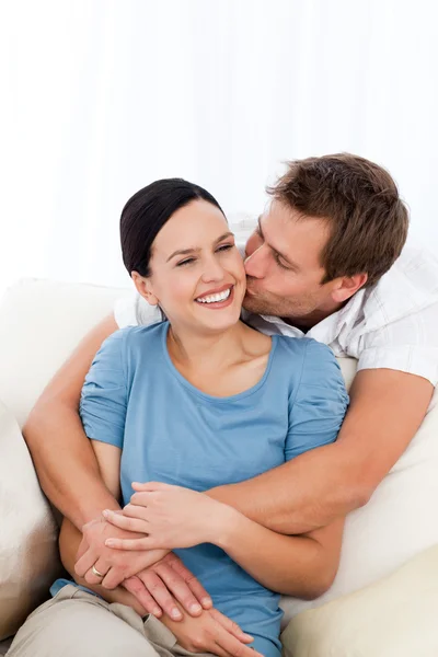 Счастливый мужчина целует свою девушку, расслабляясь на диване — стоковое фото