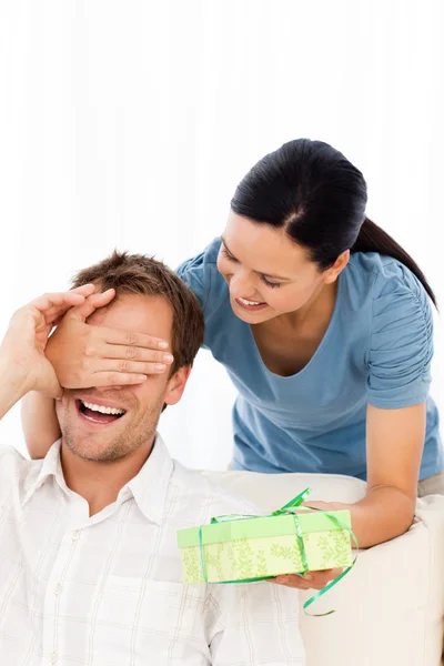 Glad kvinna ger en present till sin pojkvän medan gömma hans e — Stockfoto