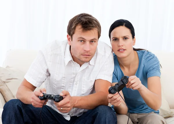 Концентрированная пара, играющая вместе в видеоигры на диване — стоковое фото