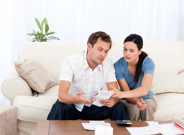 Hombre mostrando una factura a su novia sentada en el sofá — Foto de Stock