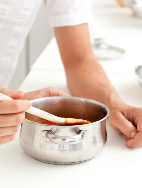 Close up of a man and woman tasting a sauce in the kitchen — Stock Photo, Image