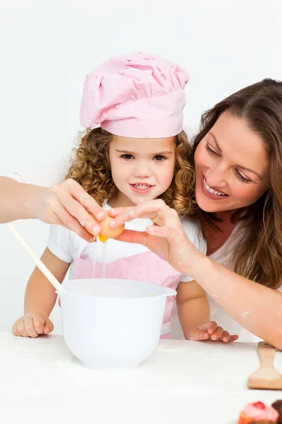 Mother showing her daughter how to break eggs — Stock Photo, Image