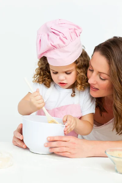 Süßes Mädchen bereitet mit ihrer Mutter einen Kuchen zu — Stockfoto