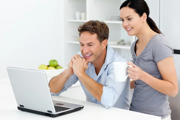 Casal feliz olhando para algo no laptop enquanto bebe c — Fotografia de Stock