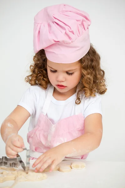 Χαριτωμένο κοριτσάκι που φτιάχνει μπισκότα στο τραπέζι. — Φωτογραφία Αρχείου