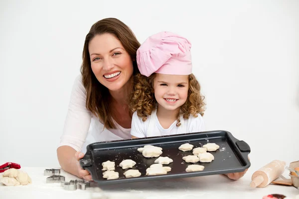Feliz madre e hija mostrando un plato con galletas — Foto de Stock