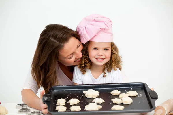 Happy little girl with her mother showing a plate with biscuits — Stock Photo, Image