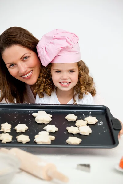 Счастливые мать и дочь держат тарелку с печеньем — стоковое фото