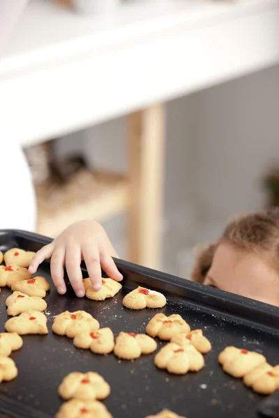 Close up of a little girl taking a cookie in the kitchen — Stock Photo, Image