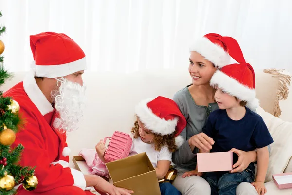 Santa geschenken geven aan zijn kinderen in de woonkamer — Stockfoto