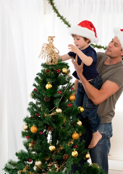 Милый сын украшает елку своим отцом — стоковое фото