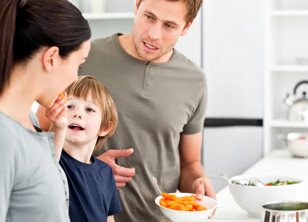 Kleine jongen zijn moeder een wortel geven bij de voorbereiding van de lunch — Stockfoto