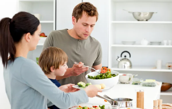 Papà che serve insalata alla sua famiglia per pranzo — Foto Stock