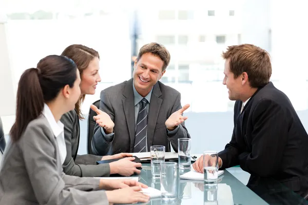 Verheugd managertalking zijn team aan een tafel — Stockfoto