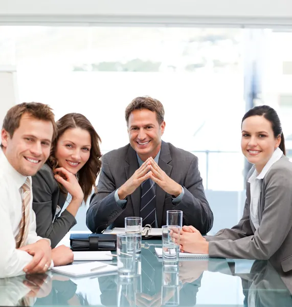 Retrato de um gerente positivo com sua equipe sentada em uma mesa — Fotografia de Stock