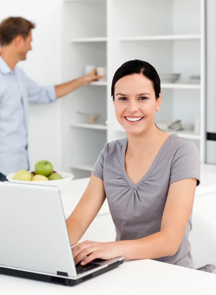 Gelukkige vrouw die werkt op de laptop in de keuken met haar boyfri — Stockfoto