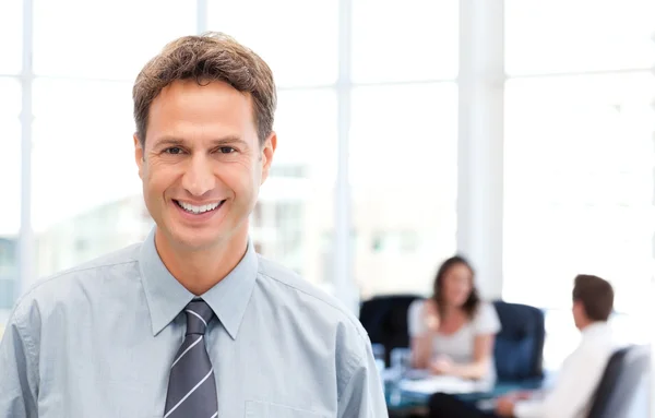 Happy businessman in the foreground while his team is working — Stock Photo, Image