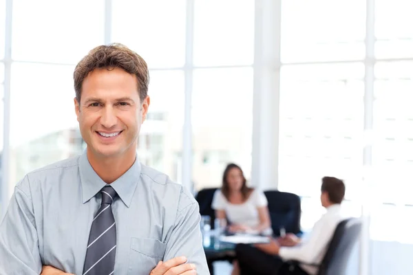 Proud businessman posing in front of his team while working