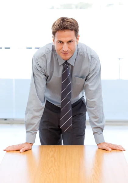 Empresário confiante posando inclinado em uma mesa — Fotografia de Stock