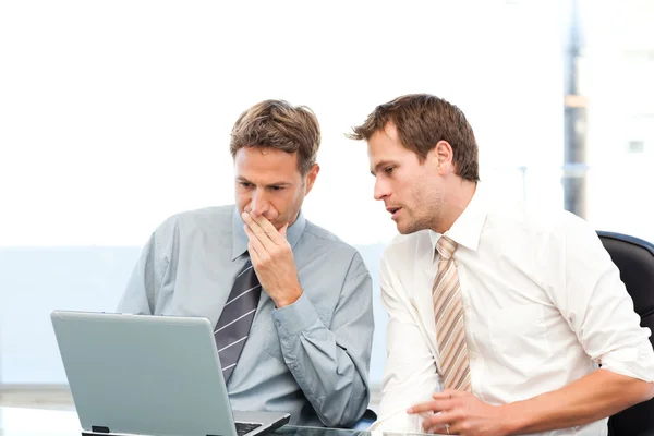 Два концентрированных бизнесмена работают вместе над ноутбуком — стоковое фото