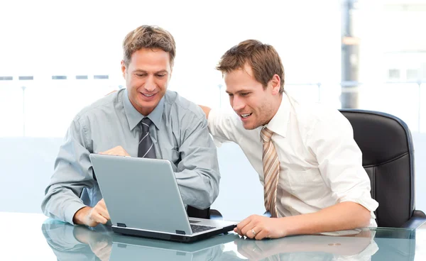 Dois empresários felizes trabalhando juntos em um laptop sentado em um — Fotografia de Stock