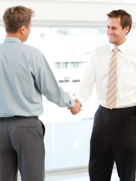 Dos hombres de negocios felices concluyendo un trato estrechando sus manos — Foto de Stock