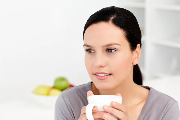 Zamyšlená žena držící šálek kávy sedí v kuchyni — Stock fotografie