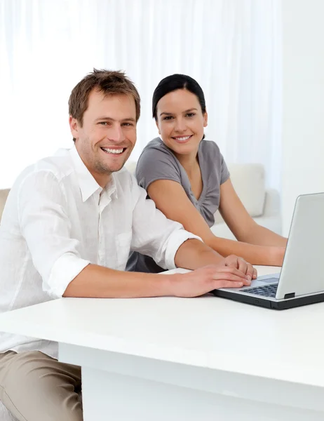 Porträt eines Paares mit Laptop an einem Wohnzimmertisch — Stockfoto