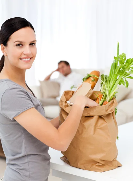 Счастливая женщина с сумками на кухне после покупок — стоковое фото