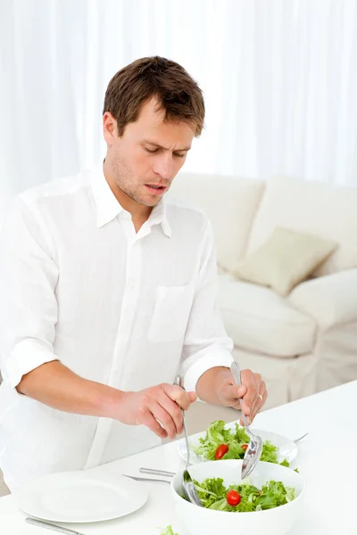 Hombre soltero sirviendo ensalada de pie en una mesa —  Fotos de Stock