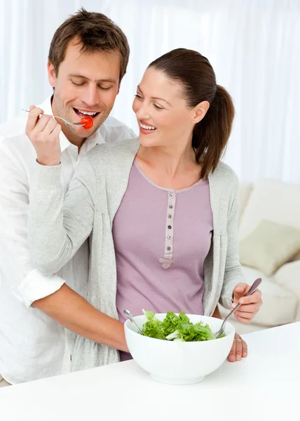 Mujer bonita dando un tomate a su novio mientras prepara un — Foto de Stock