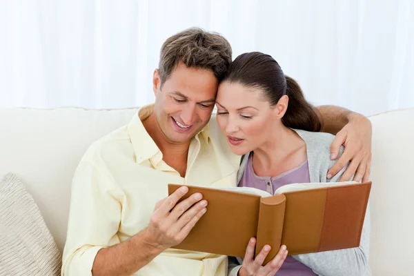 Homem e mulher atentos olhando para um álbum de fotos no sofá — Fotografia de Stock