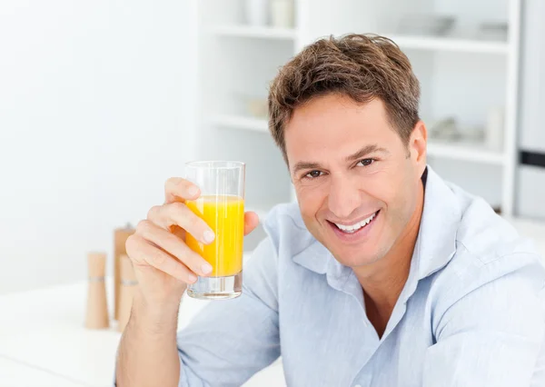 Przystojny mężczyzna pije sok pomarańczowy w kuchni — Zdjęcie stockowe