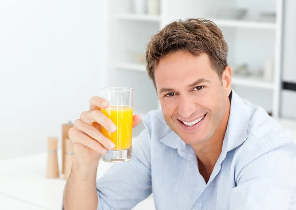 stock image Handsome man drinking an orange juice in the kitchen