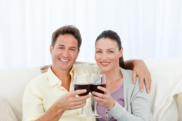 Portret parę szczęk szklanki czerwonego wina na kanapie — Zdjęcie stockowe