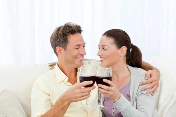 Страстная пара пьет красное вино, расслабляясь на диване — стоковое фото