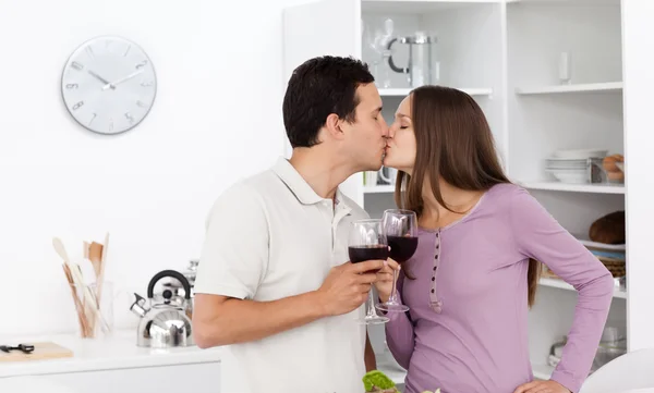 Nettes Paar küsst sich mit einem Glas Rotwein in der Hand — Stockfoto