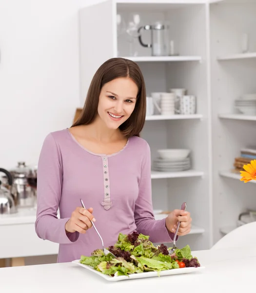 Vacker kvinna förbereder en sallad stående i köket — Stockfoto