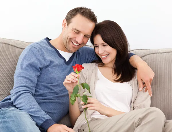 Porträt eines schönen Paares, das eine rote Rose betrachtet — Stockfoto